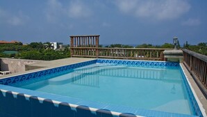 A rectangular pool with blue tiles and a decorative edge, surrounded by a wooden deck and a railing. - Mission Gate 3B, 2-bedroom condo by Island House Vacation Rentals (West Bay)