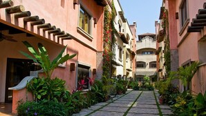 A narrow pathway flanked by buildings with balconies, leading to a central courtyard. - Mission Gate 3B, 2-bedroom condo by Island House Vacation Rentals (West Bay)
