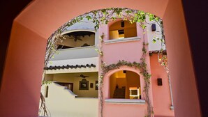 Un immeuble à plusieurs étages, doté de fenêtres en arc de cercle et de balcons, le tout recouvert de lierre.