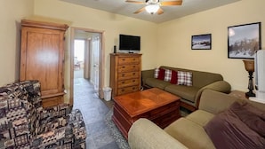 A living room with a sofa, a coffee table, a television, and a cabinet.