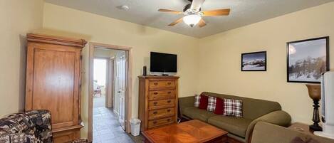 A living room with a sofa, a coffee table, a television, and a cabinet.
