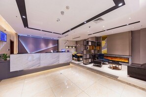 Un espace d’accueil moderne doté d’un comptoir en marbre, de sièges, d’une cheminée et d’un téléviseur fixé au mur.