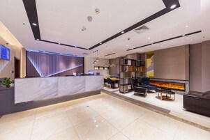 A modern reception area with a marble counter, seating, a fireplace, and a wall-mounted TV.