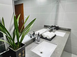 Une salle de bain moderne avec deux lavabos, un miroir et une plante en pot.