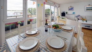Un coin repas avec une table dressée pour quatre personnes, de grandes fenêtres et une vue sur un quai.