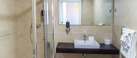 A modern bathroom with a glass-enclosed shower, a sink with a mirror above, and a towel rack on the wall.