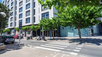A modern building with a large glass facade, a crosswalk, and parked vehicles.