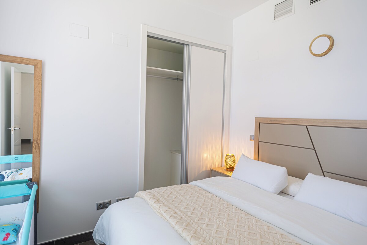 Un dormitorio con cama, armario y mesita de noche con lámpara.