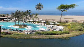 Ein Resort mit Pool, Liegestühlen, Sonnenschirmen und Blick auf den Strand.
