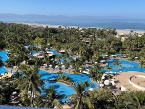 Un complexe hôtelier doté de plusieurs piscines, entouré de palmiers et offrant une vue sur la plage.