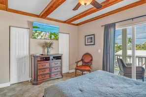 A bedroom with a bed, a dresser, a chair, a painting, and a balcony with a view. - Oceanview Rooftop Retreat  3BR 3BA in Marathon FL (Marathon)