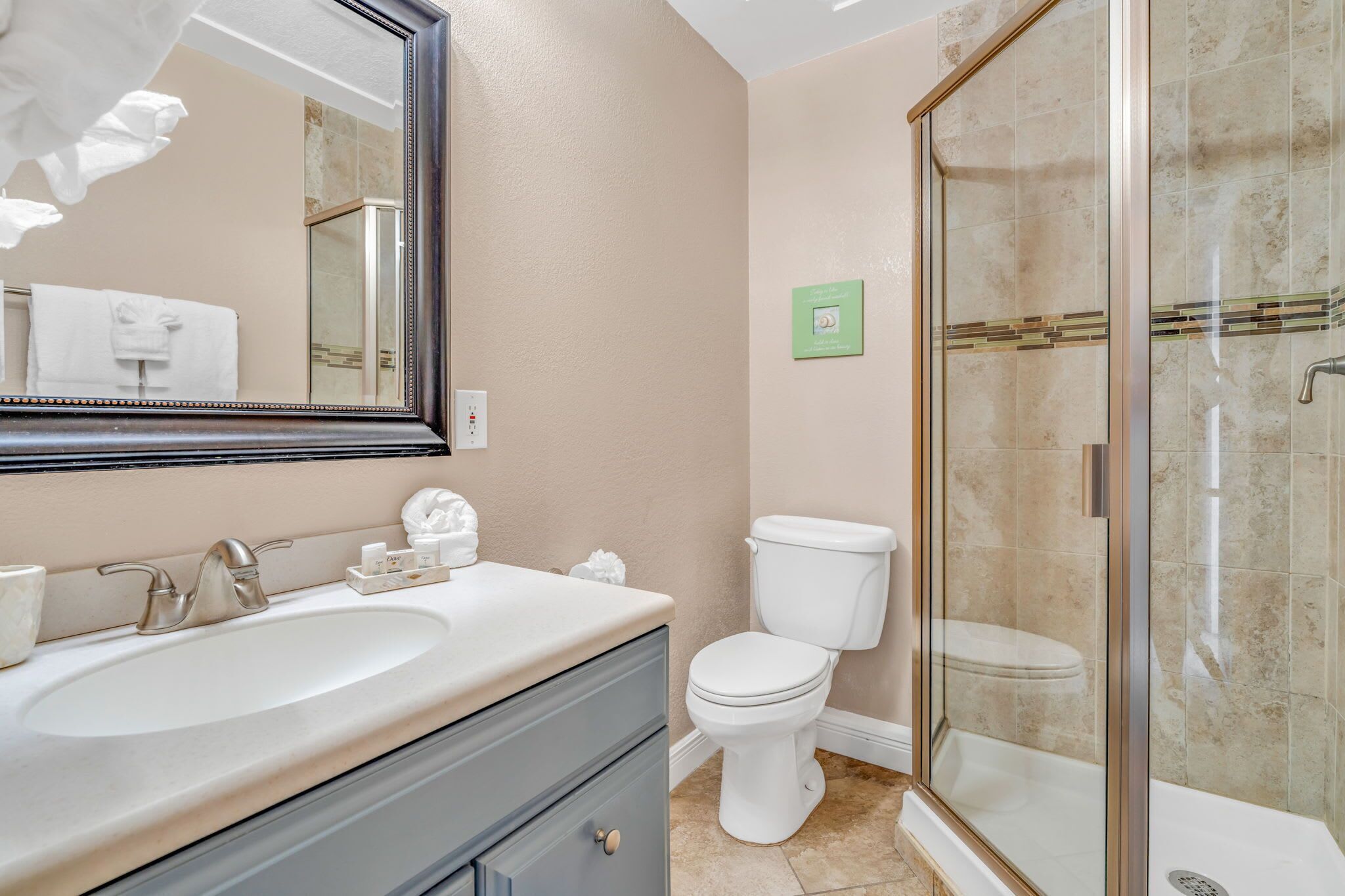 A bathroom with a double sink, a toilet, and a glass-enclosed shower.