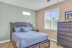 A bedroom with a bed, nightstand, dresser, and window with blinds. - Oceanview Villa w/ Private Rooftop & Pool (Marathon)