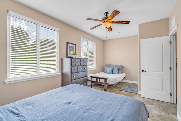 A bedroom with a bed, dresser, nightstand, and a ceiling fan.