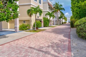 A paved walkway lined with palm trees and greenery, leading to a building with a beige facade and multiple windows. - Oceanview Rooftop Retreat  3BR 3BA in Marathon FL (Marathon)