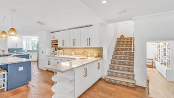 A modern kitchen with white cabinetry, a central island, and a staircase with patterned steps.