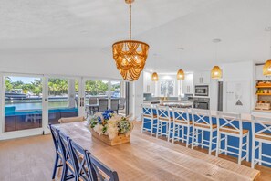 Une cuisine moderne avec des meubles blancs, un îlot central et des luminaires suspendus.