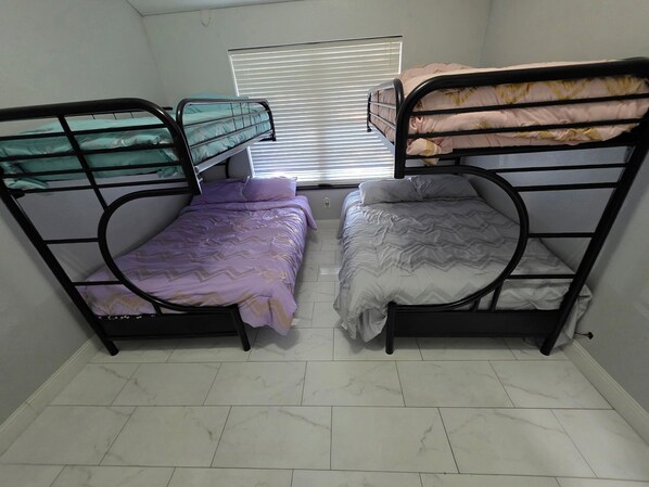 A dormitory room with two bunk beds, a window with blinds, and a tiled floor. - Yukon home (Yukon)
