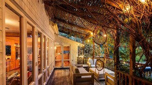 A covered outdoor area with wooden flooring, seating, and a pergola with string lights.