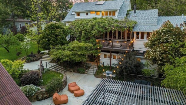 A house with a covered patio, outdoor seating, and a garden.