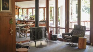 A cozy room with a wood-burning stove, a comfortable chair, and a dining area with a table and chairs.