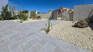 A modern outdoor area with a paved walkway, stone walls, and a small gate. - Home Geranio With Private Garden (Castelsardo)
