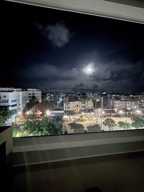 A nighttime view from a window overlooking a residential area with buildings and a street.