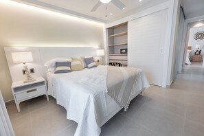 A modern bedroom with a large bed, bedside tables, a wardrobe, and a ceiling fan. - Luxury Corner Penthouse — Ocean Views from Two Floors + Content Creator Hub (Punta Cana)