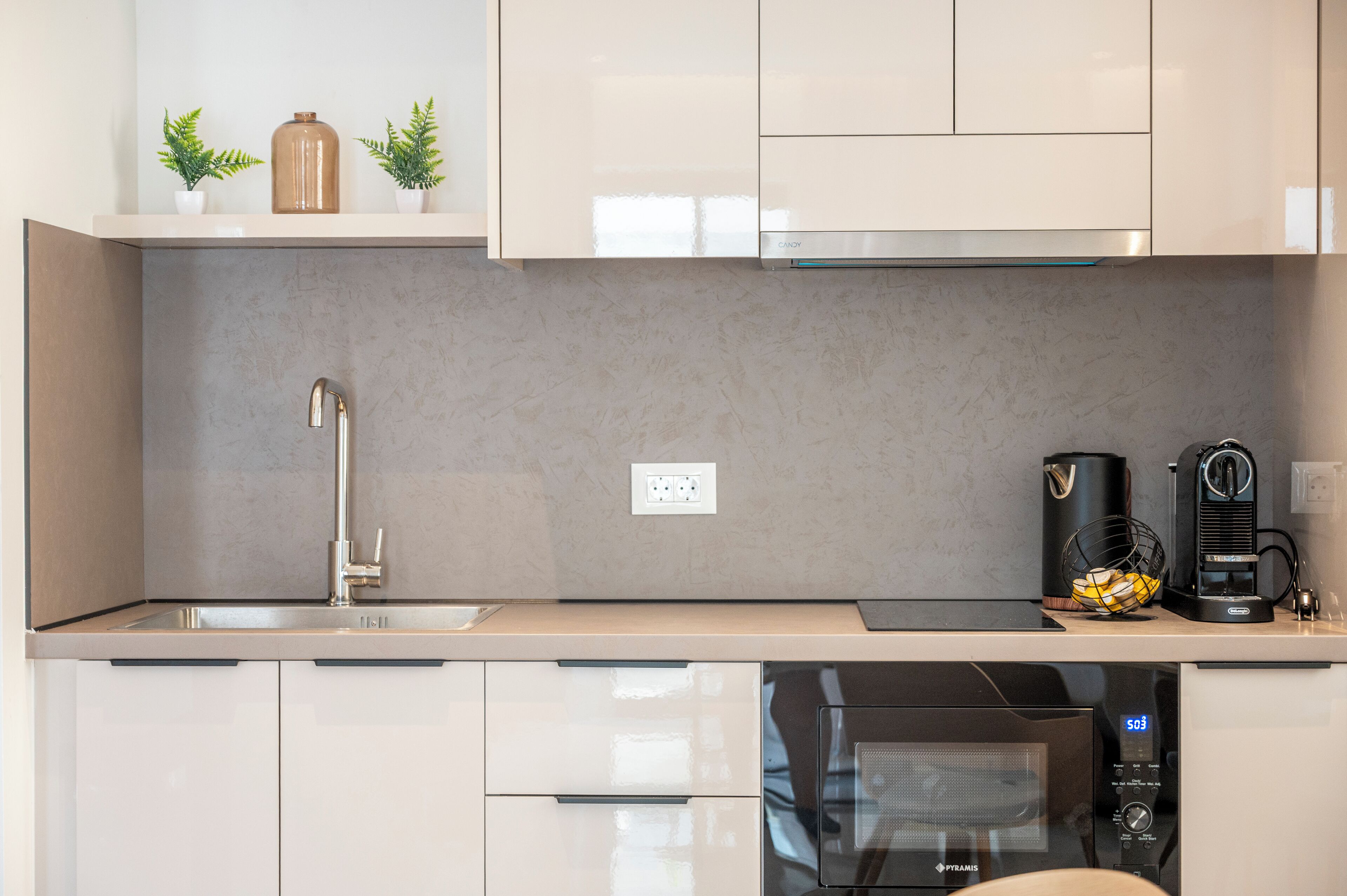 A modern kitchen with a stainless steel sink, a coffee maker, and a microwave.