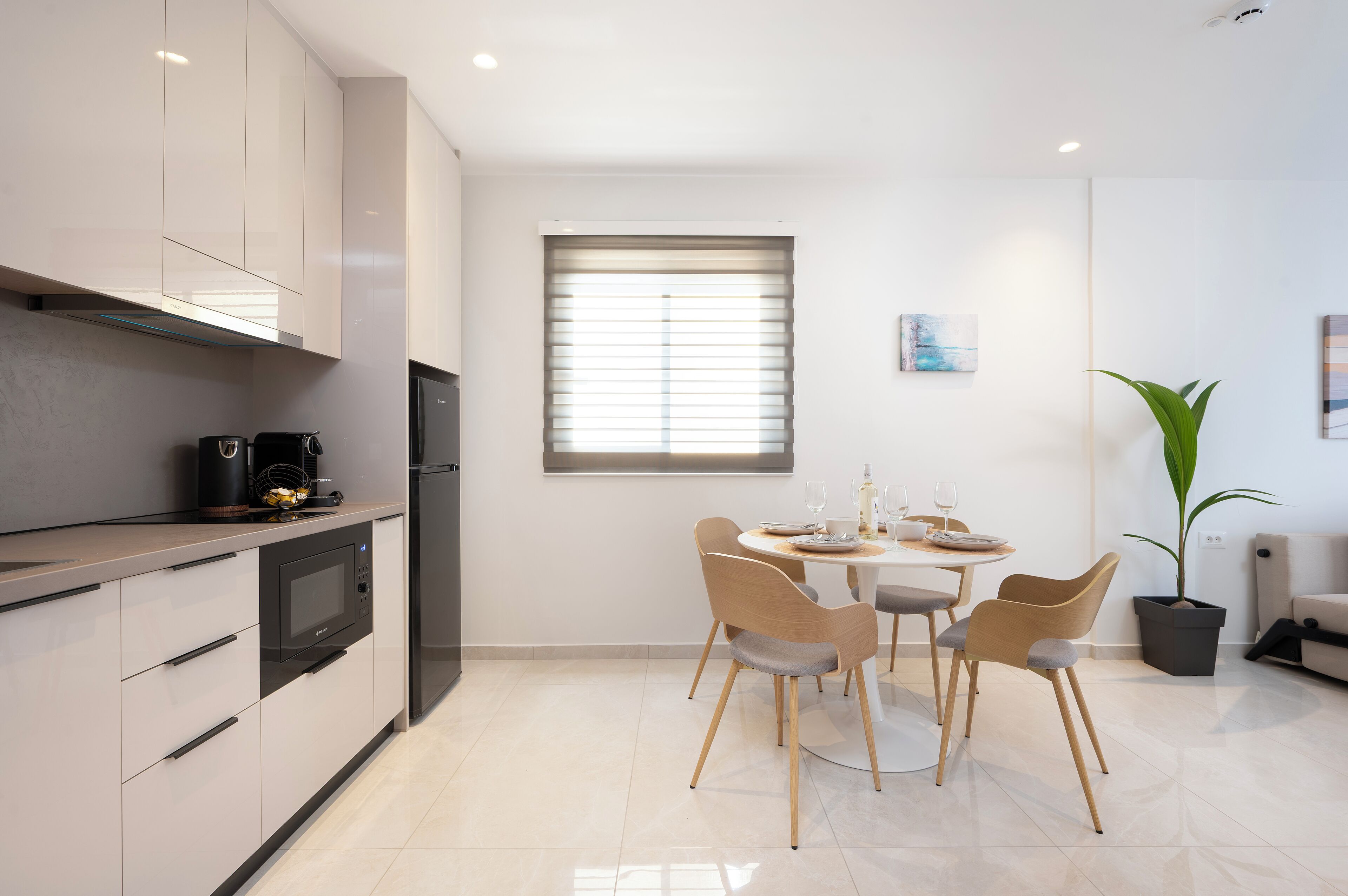 A modern kitchen with a dining area, featuring a microwave, stove, and a dining table with chairs.