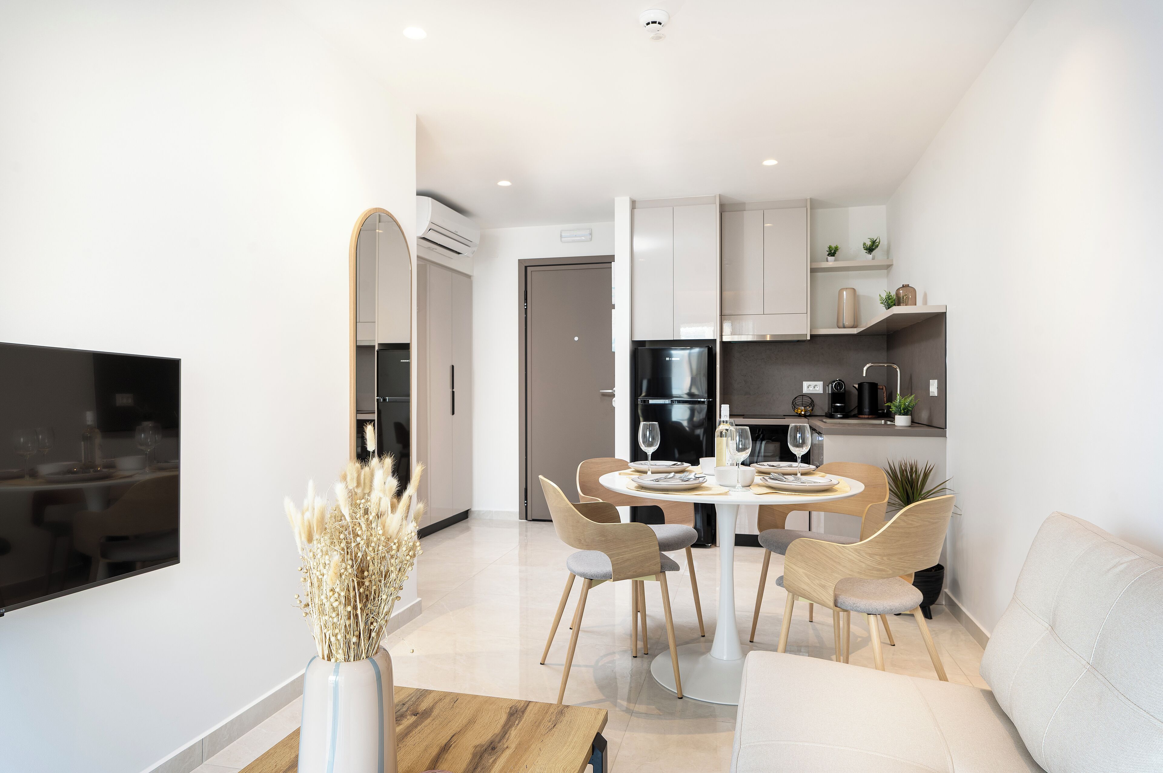 A modern kitchen with white cabinets, a black refrigerator, and a dining area with a round table and chairs.