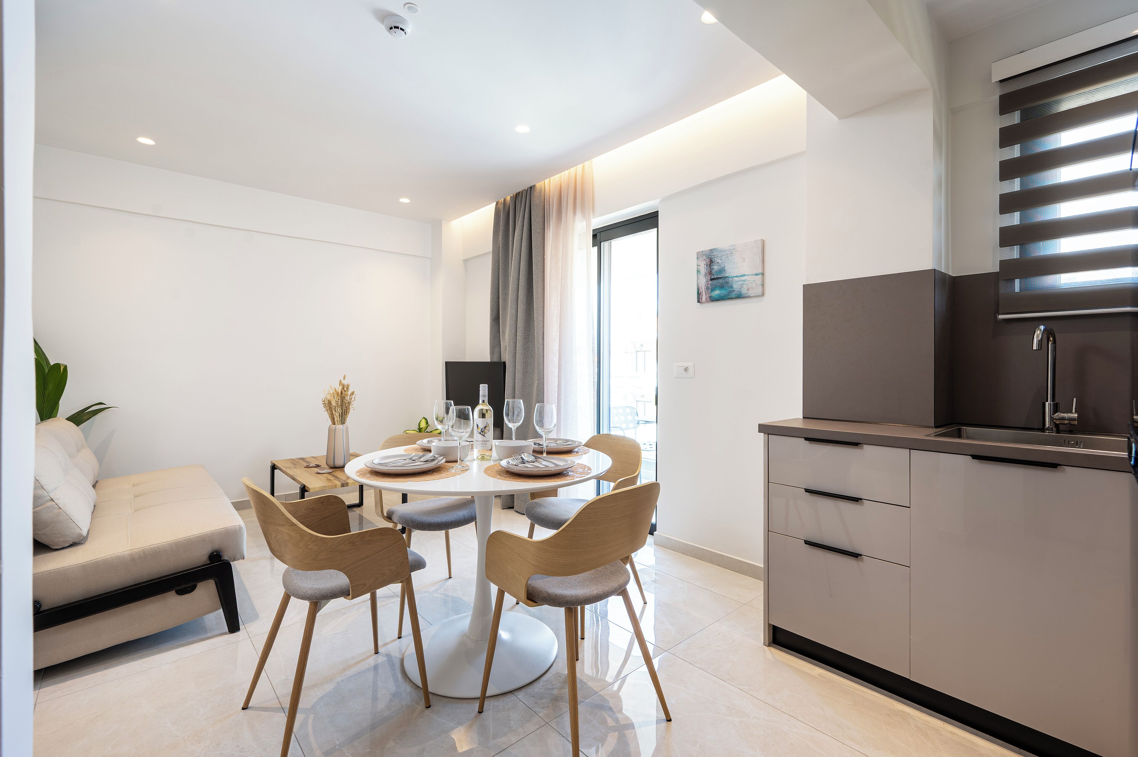 Een moderne eethoek met een ronde tafel, vier stoelen en een bank.
