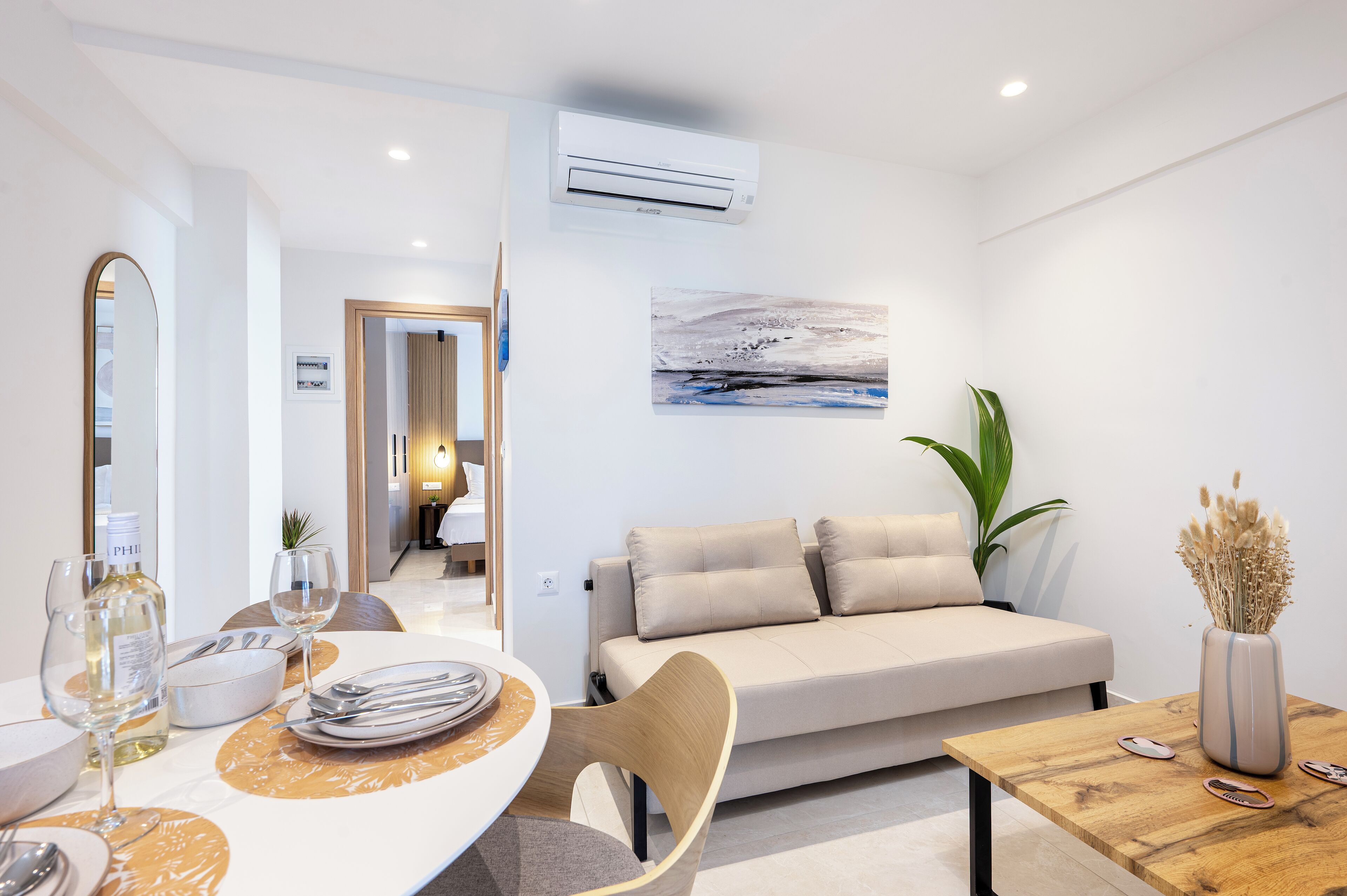 A modern living room with a sofa, dining table, and a painting on the wall.