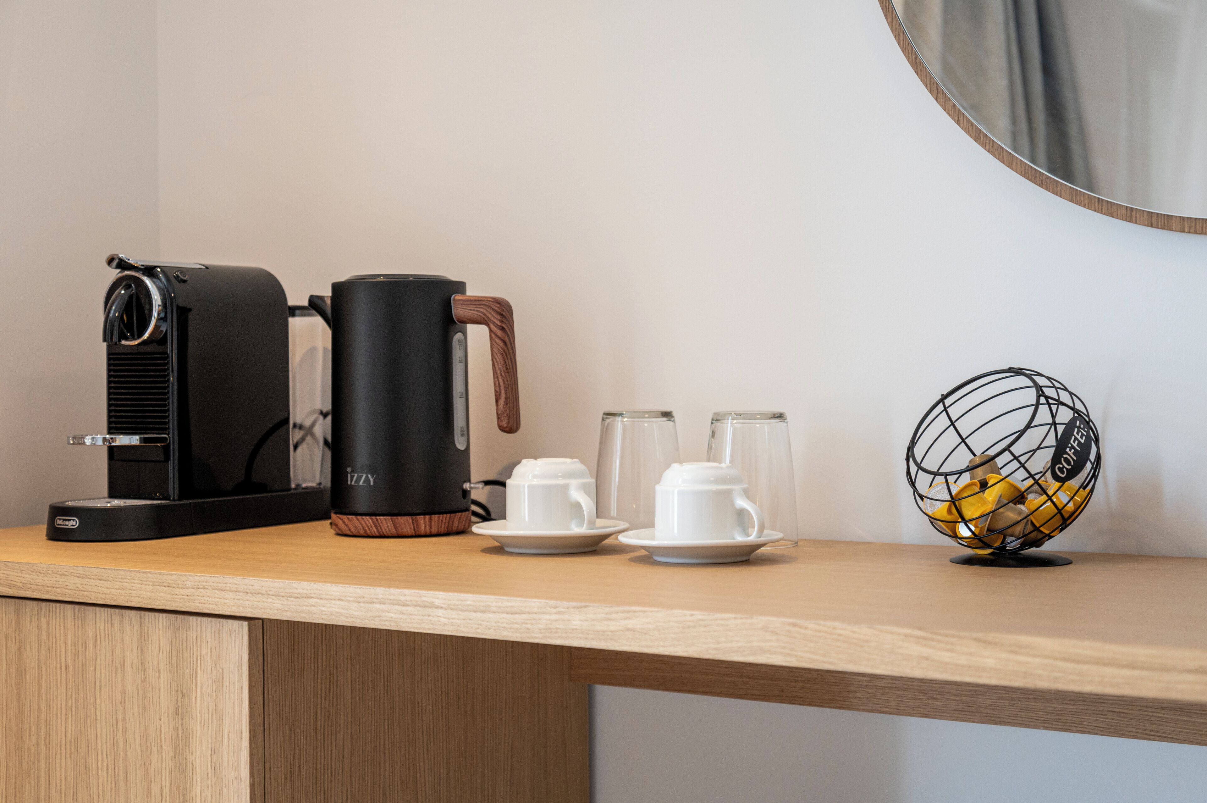 Uma cafeteira, duas chávenas brancas e um café bola sobre uma superfície de madeira.