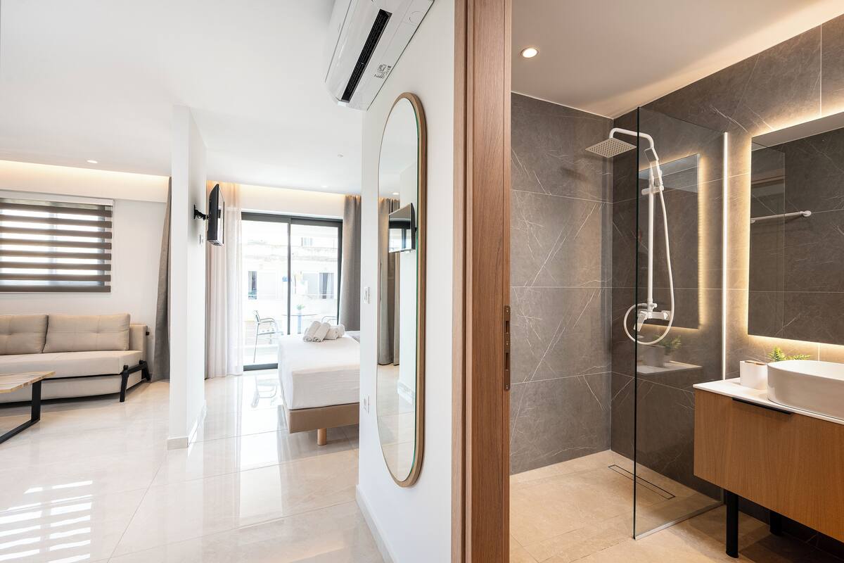 Un baño moderno con ducha envuelta en vidrio, un espejo grande y un tocador con lavamanos.