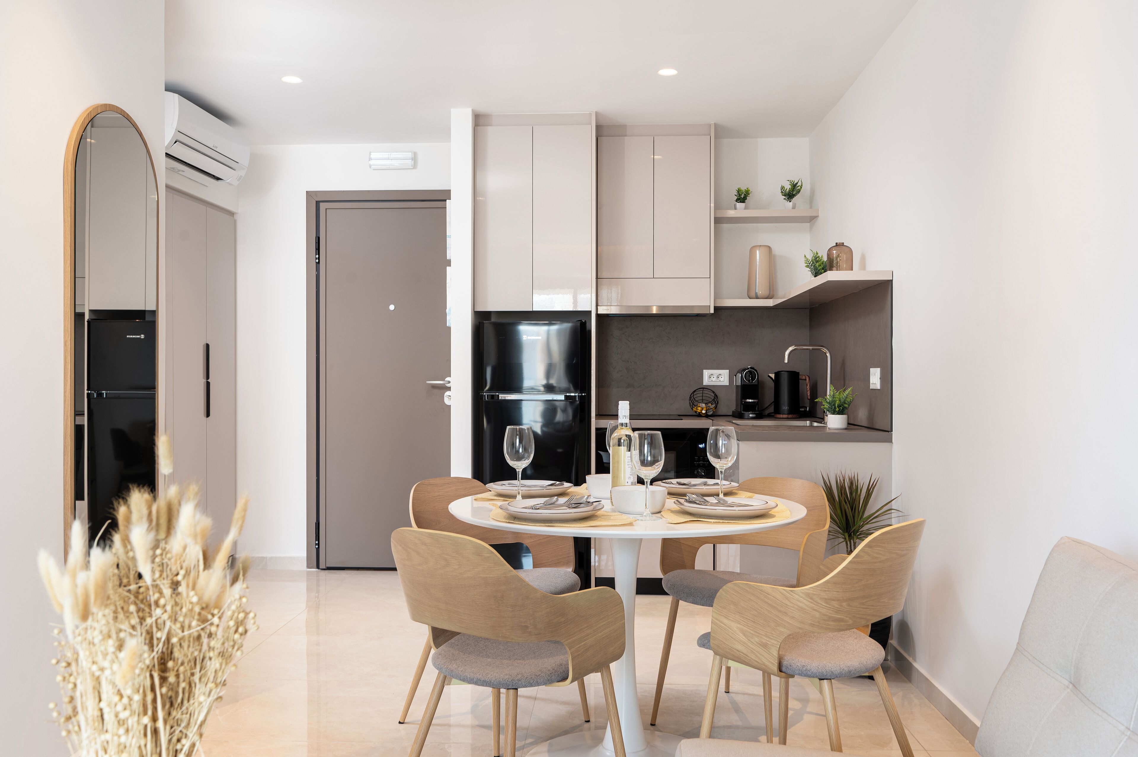 A modern kitchen with white cabinets, a black refrigerator, and a dining area with a round table and four chairs.