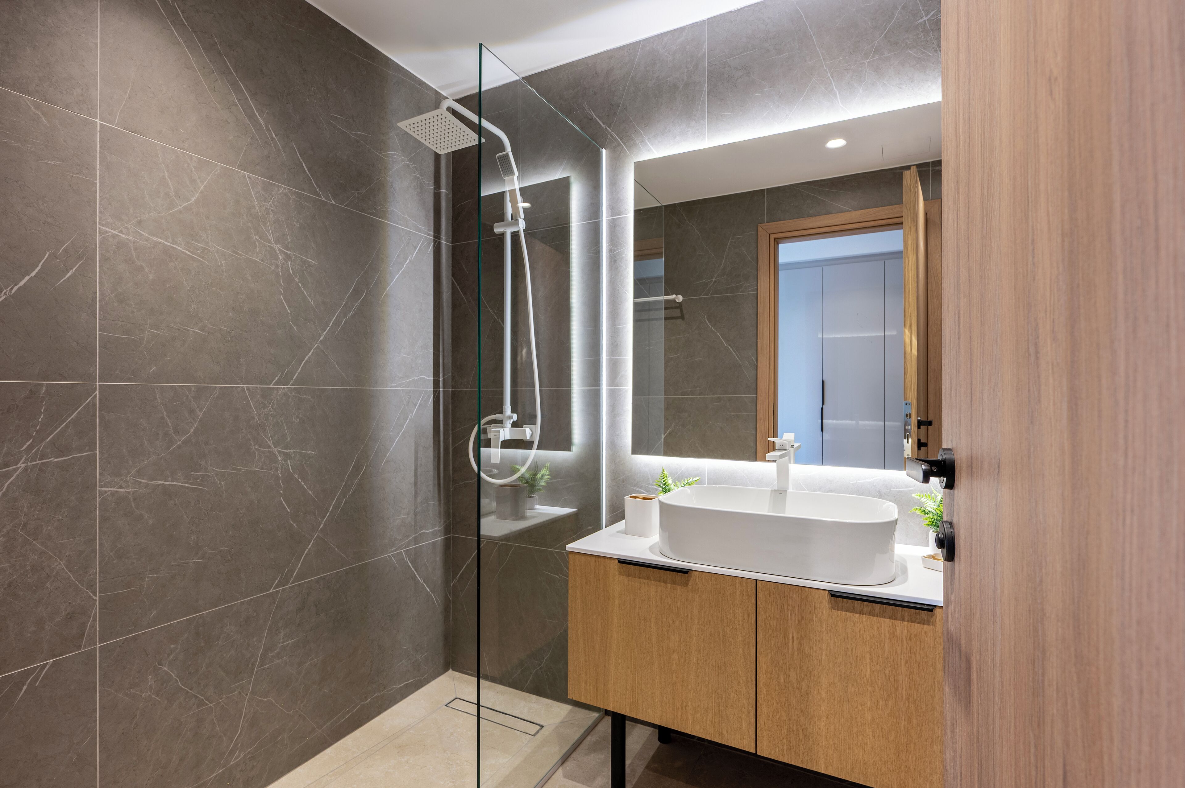 A modern bathroom with a glass-enclosed shower, a large sink, and wooden cabinetry.