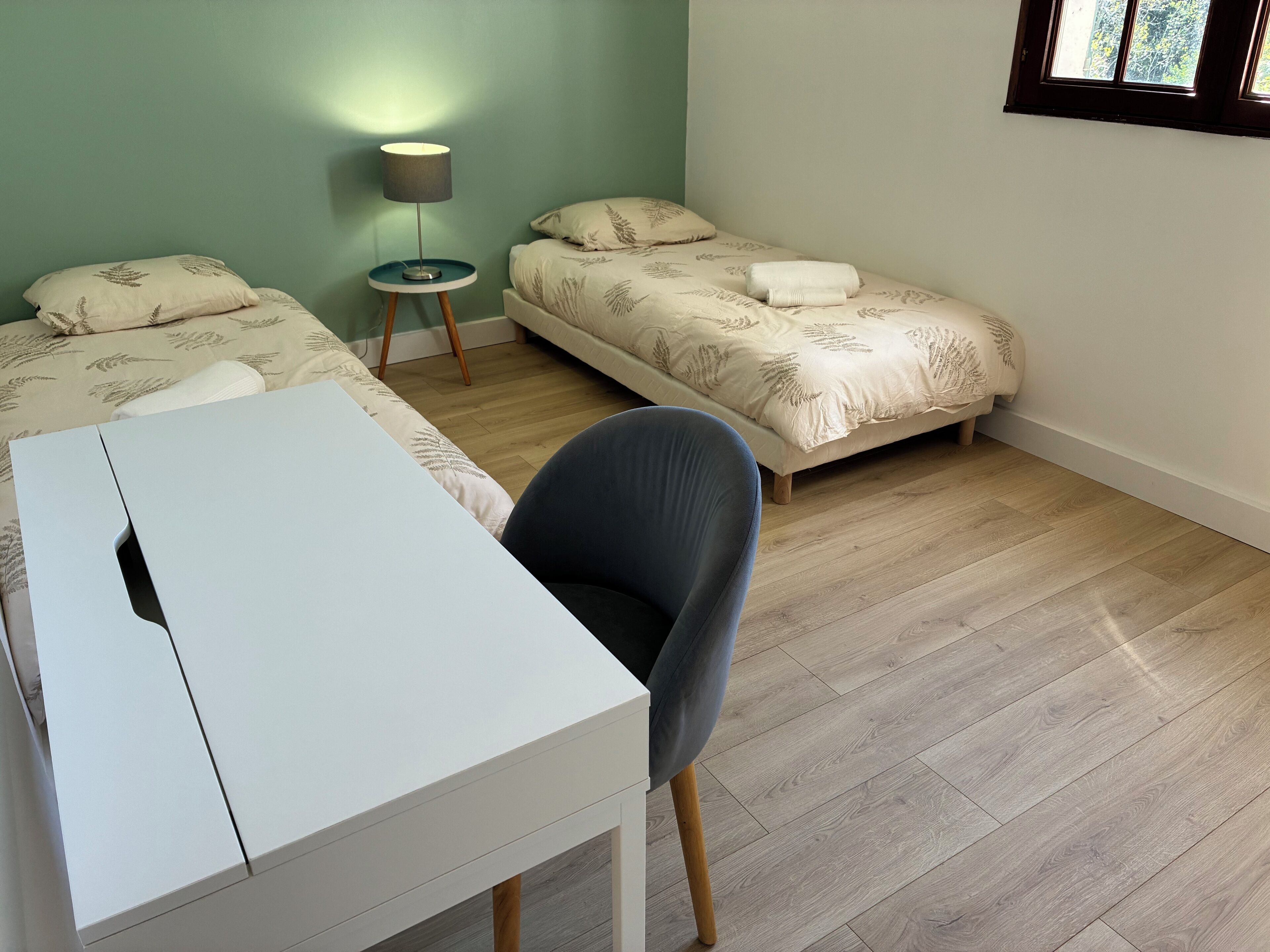 A room with two beds, a desk, and a chair.