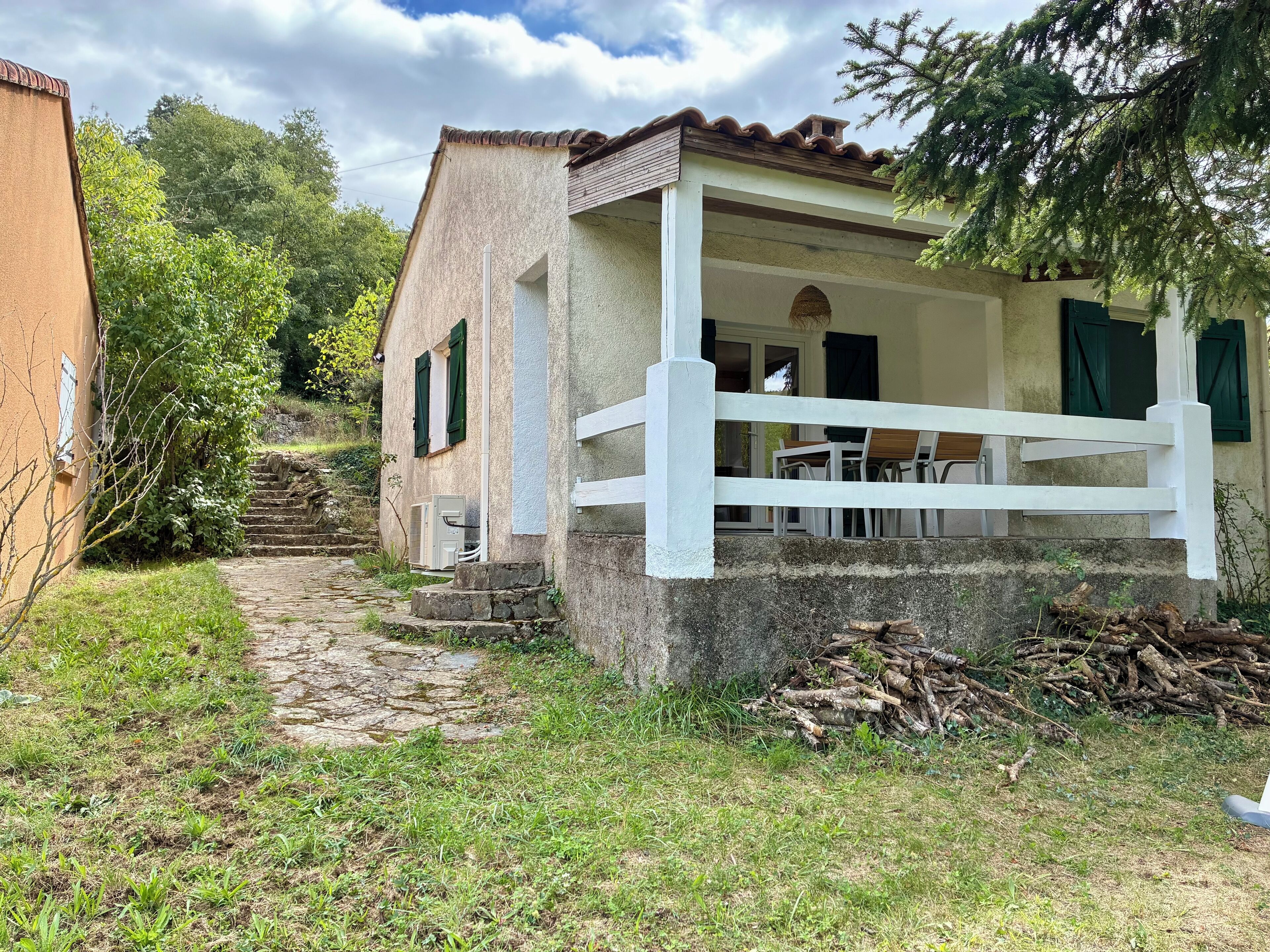 Une maison de campagne rustique, avec un chemin de pierres menant à un porche blanc.