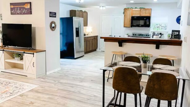 Eine moderne Küche mit weißen Schränken, einem schwarzen Kühlschrank und einem Essbereich mit Tisch und Stühlen.