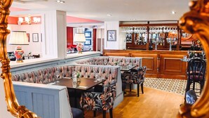 A restaurant with booths, a bar area, and a patterned floor. - The Raven (Claines)