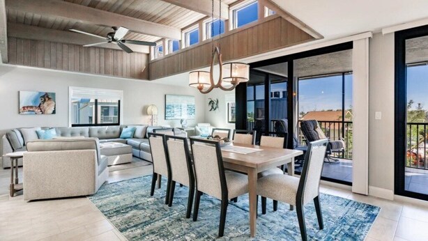Un vaste espace de vie doté d’un haut plafond, une table à manger avec des chaises, un canapé et un balcon avec des sièges d’extérieur.
