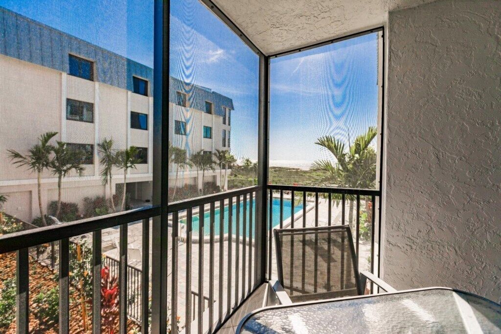 A balcony with a view of a swimming pool and a building.