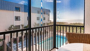 Un balcon donnant sur une piscine et un immeuble.