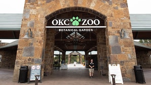 The entrance to OKC Zoo Botanical Garden with stone arches, a welcome sign, and informational signs. - Cozy Urban Getaway Near Paseo Arts 31A (Oklahoma City)