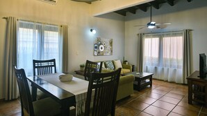 Una sala de estar con una mesa de comedor, sillas, un sofá, un televisor y un ventilador de techo.