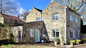 A stone building with a green door, windows, and a bench outside. - Cottage in Bellerby With Private Hot Tub (Leyburn)