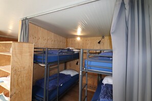 Ein Schlafsaalzimmer mit Etagenbetten, Holzwänden und einer Metalldecke.