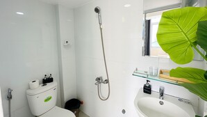 A modern bathroom with a shower, toilet, sink, and a large mirror. - Centana Hotel & Apartments (Ho Chi Minh City)