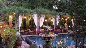 Un giardino con piscina, fontana per uccelli e area salotto all'aperto.